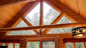 A cabin with a wooden interior, large windows, and a ceiling fan.