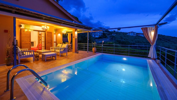Une piscine extérieure dotée d’une terrasse en bois, d’un espace détente et offrant une vue sur le paysage environnant.