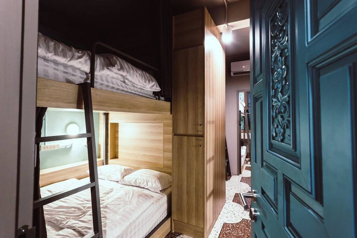 A bunk bed room with a wooden wardrobe and a teal door.