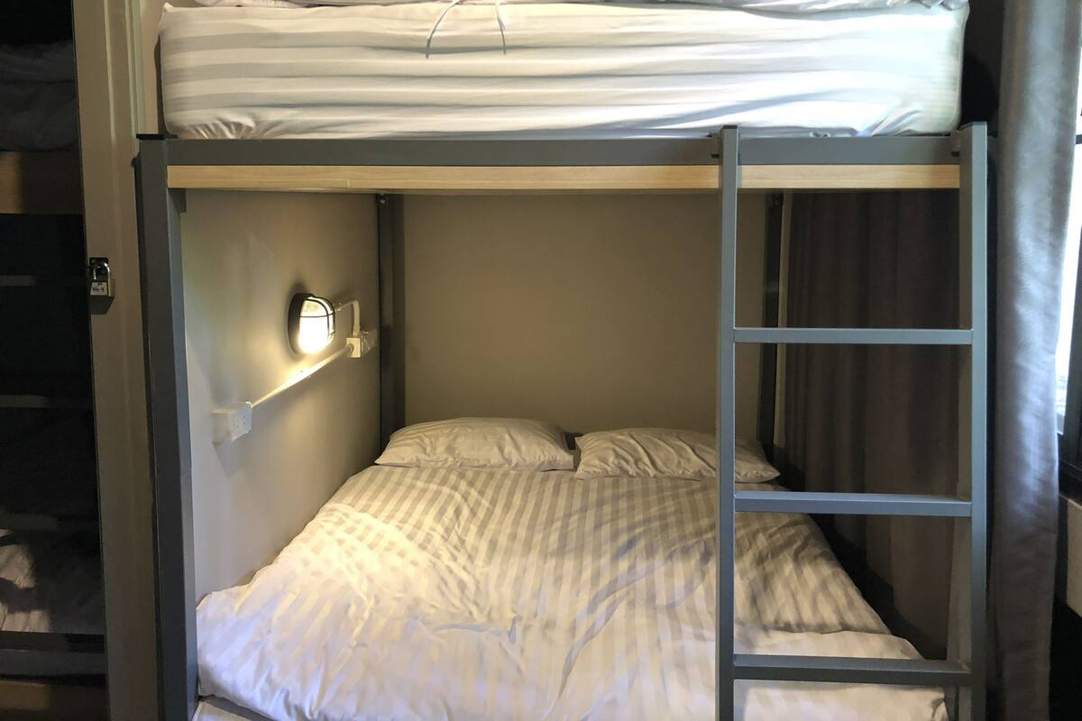 A bunk bed with a headboard and a bedside table with a lamp.