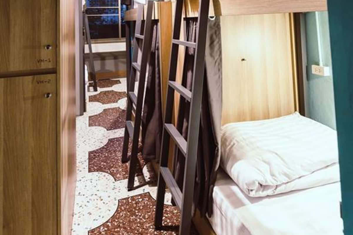A narrow corridor with bunk beds, wooden cabinets, and a patterned floor.