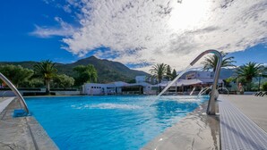 A swimming pool with clear blue water, surrounded by a tiled deck and palm trees. - Rescator Resort 329 - One Bedroom Apartment, Sleeps 4 (Roses)