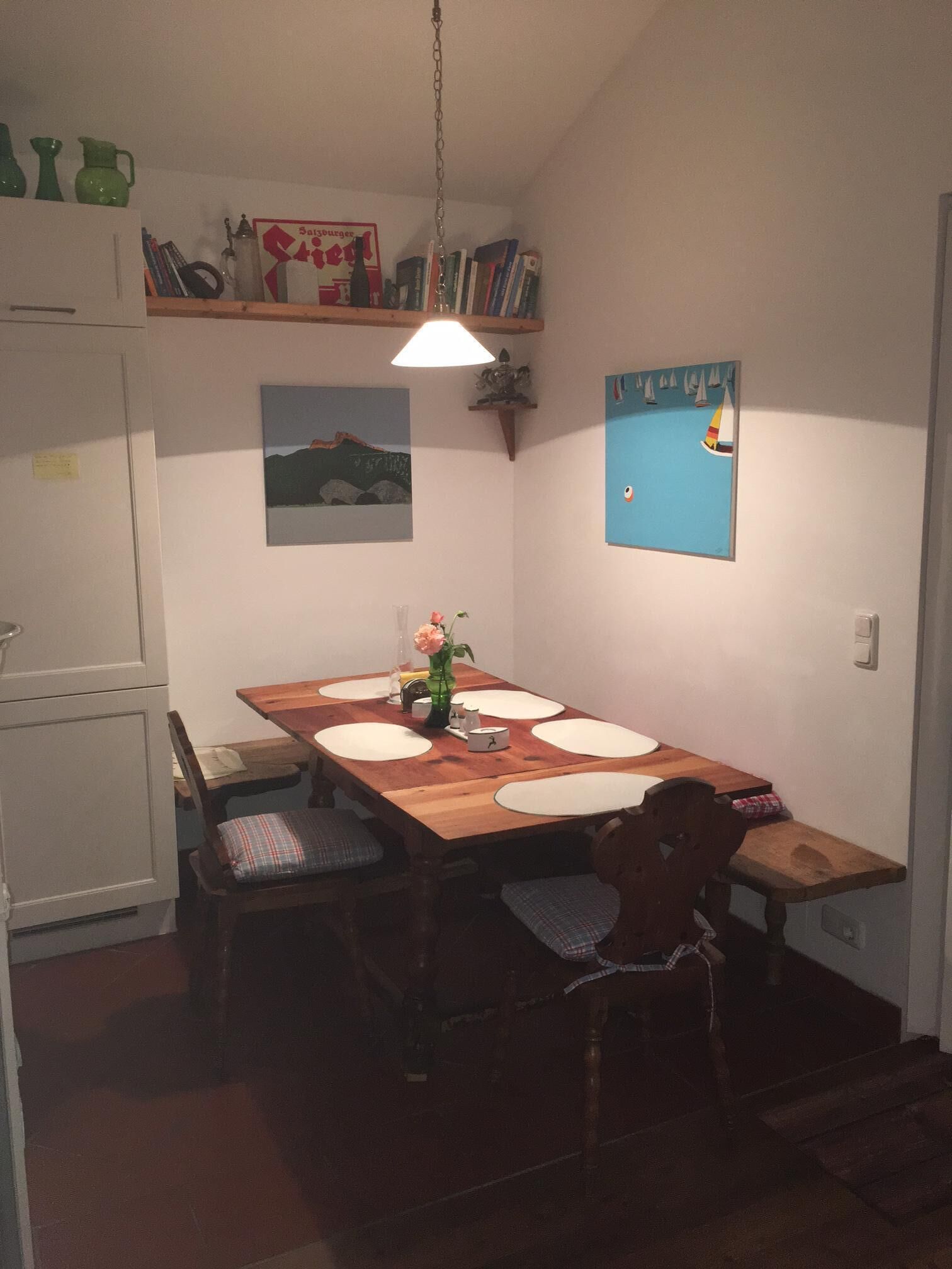A dining area with a wooden table, chairs, and a hanging light fixture.