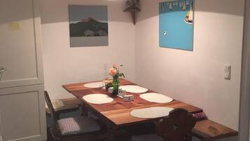 A dining area with a wooden table, chairs, and a hanging light fixture.