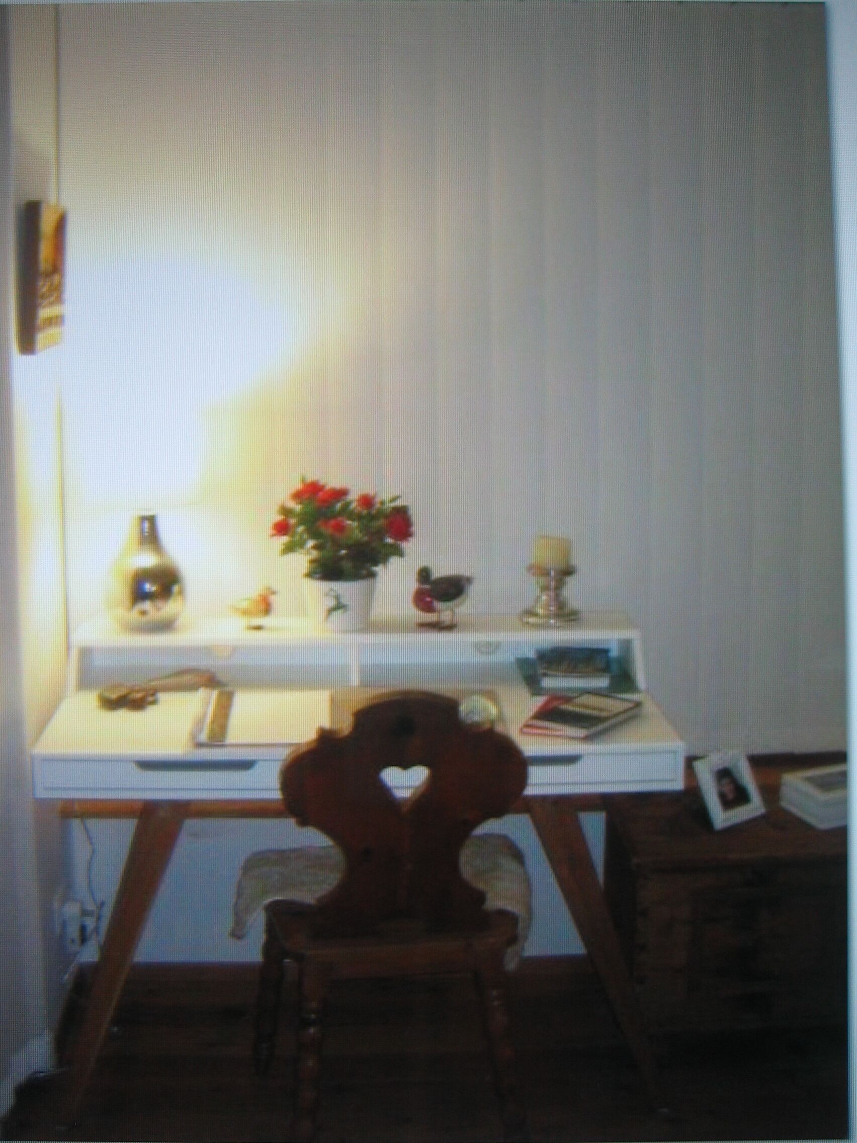 A room with a desk, chair, and a window with curtains.