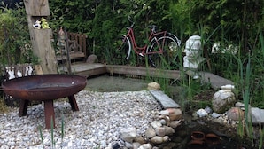 A garden with a fire pit, a pond, and a bicycle.