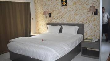 A neatly made bed with white linens, a headboard, and two bedside lamps.