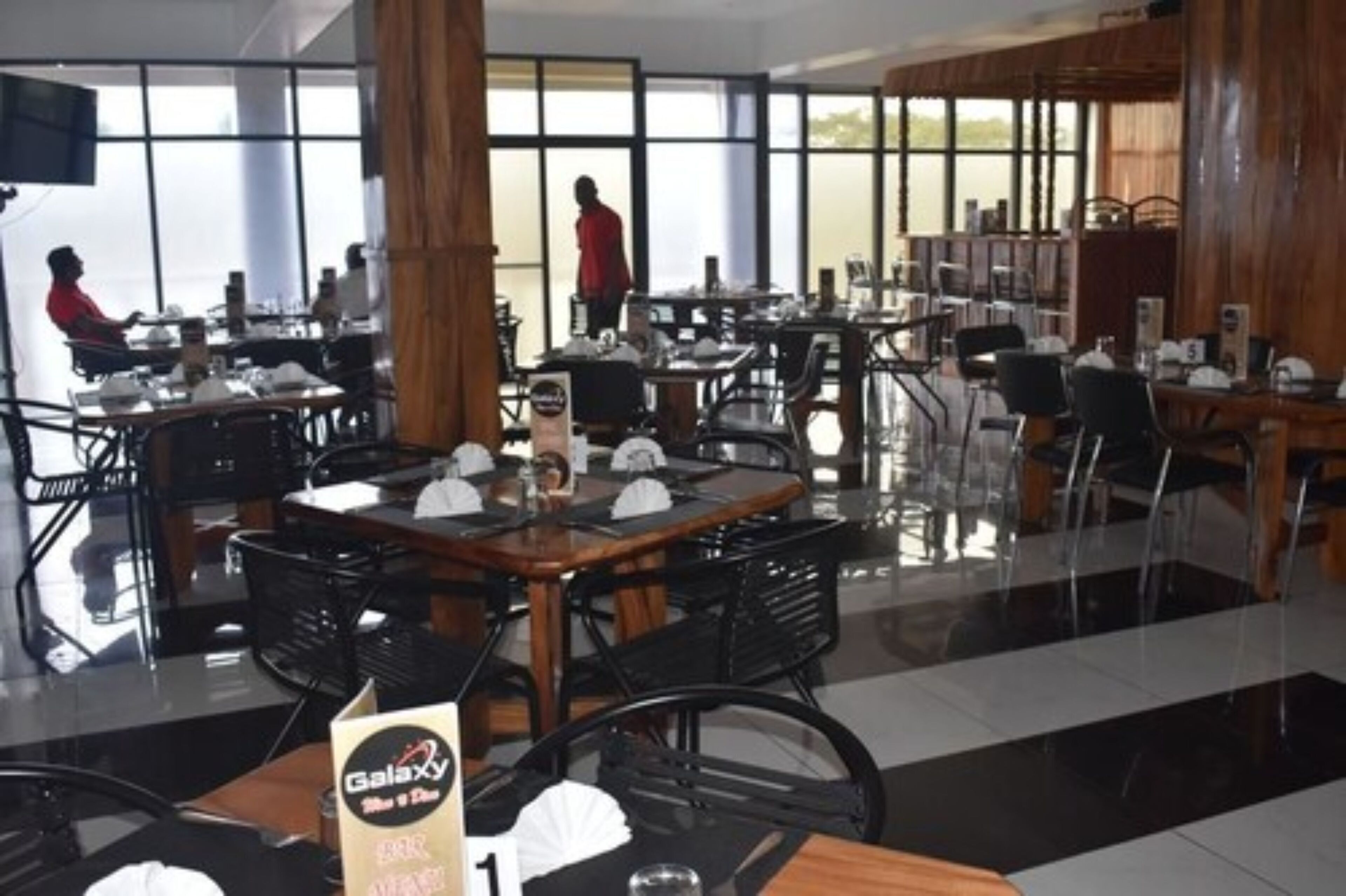 A restaurant with multiple tables and chairs, large windows, and a modern interior design.