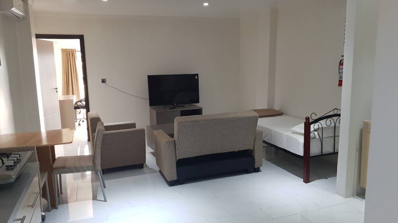 A modern living room with a sofa, a TV, and a bed.