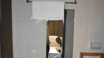 Un baño con un lavamanos blanco, un espejo y un perchero para toallas.