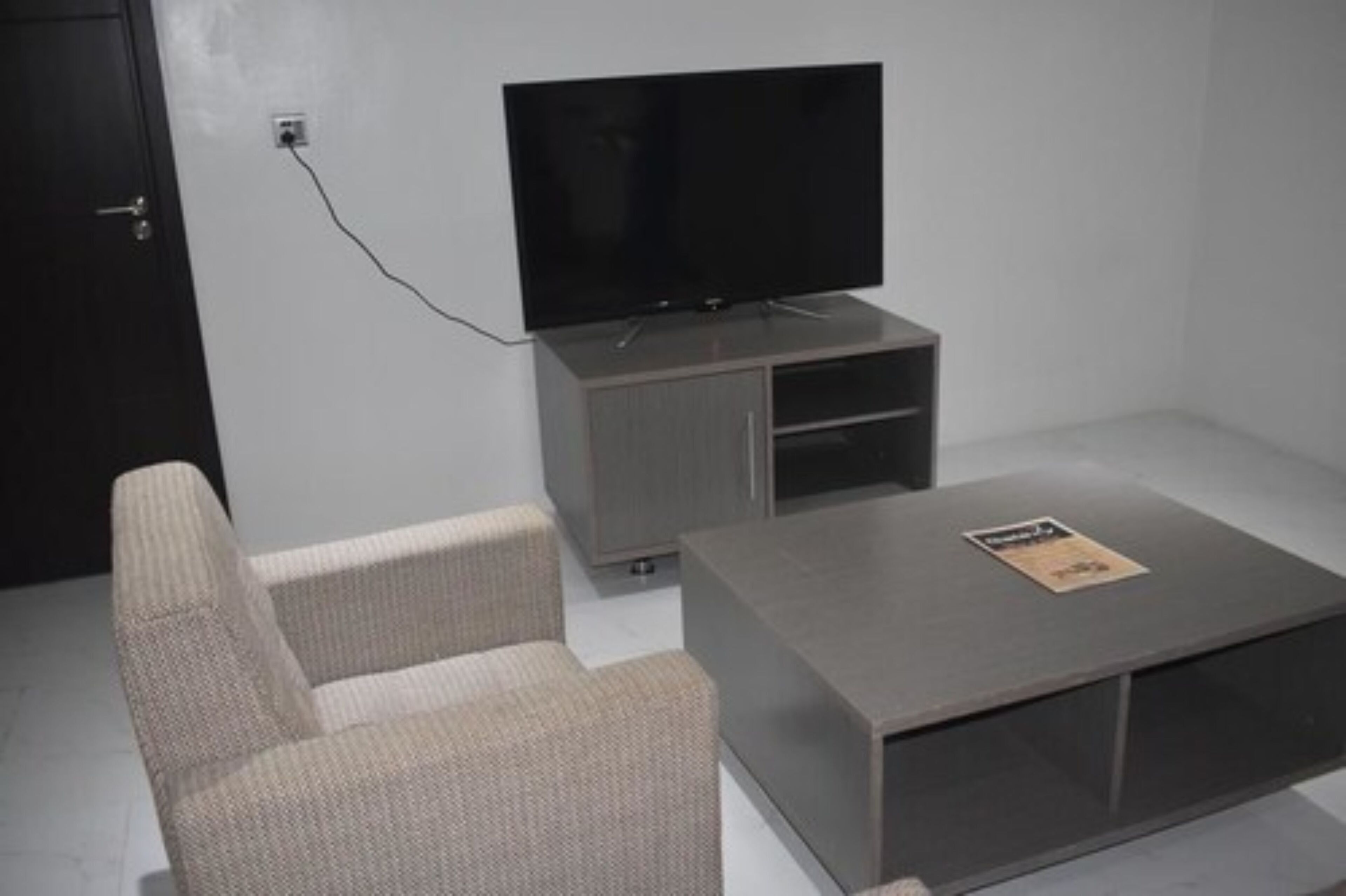 A modern living room with a flat-screen TV, a grey sofa, and a coffee table.