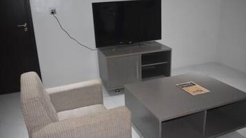 A modern living room with a flat-screen TV, a grey sofa, and a coffee table.