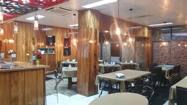 A restaurant interior with wooden paneling, tables, chairs, and hanging pendant lights. - Galaxy Hotels & Apartments (Labasa)