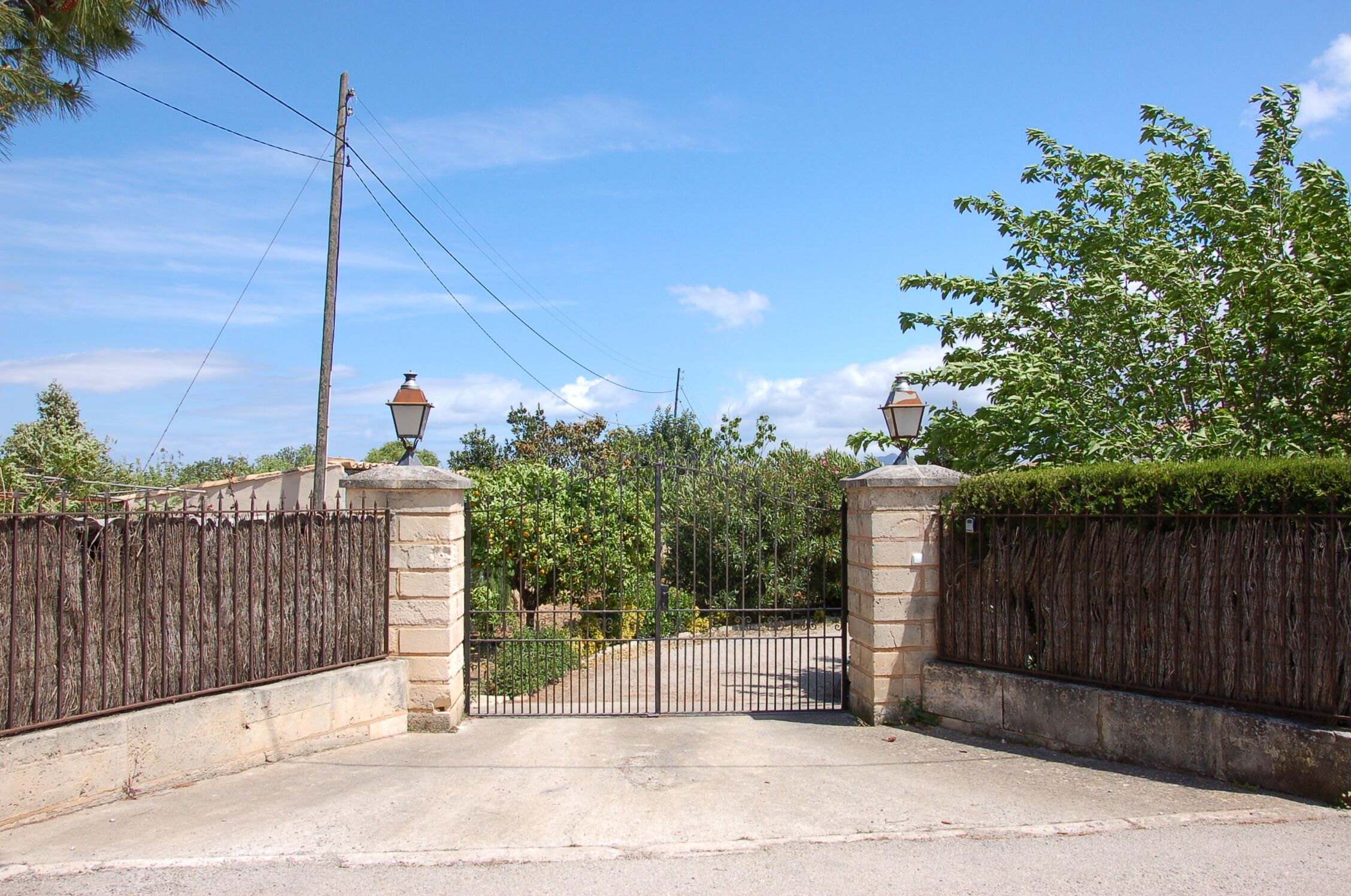 A gated entrance with a metal gate, stone pillars, and a street lamp.