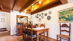 Un comedor con mesa y sillas de madera, un espejo y platos decorativos colgados en la pared.
