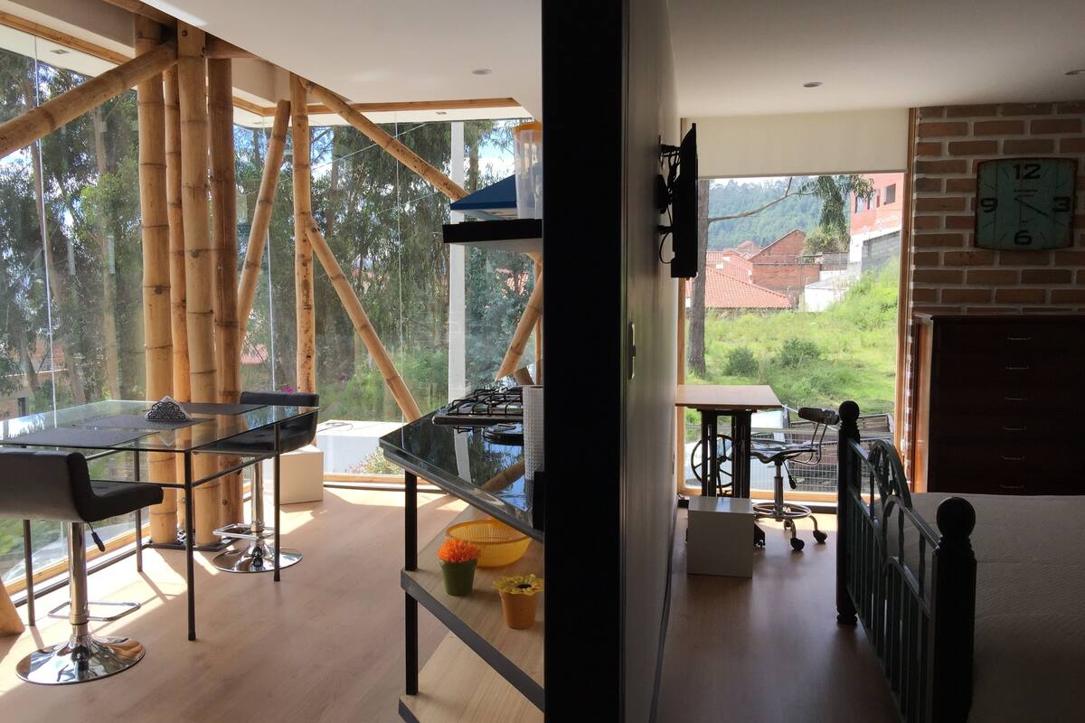 Ett modernt kök med en gasspis, ett matbord i trä och utsikt över omgivningen.