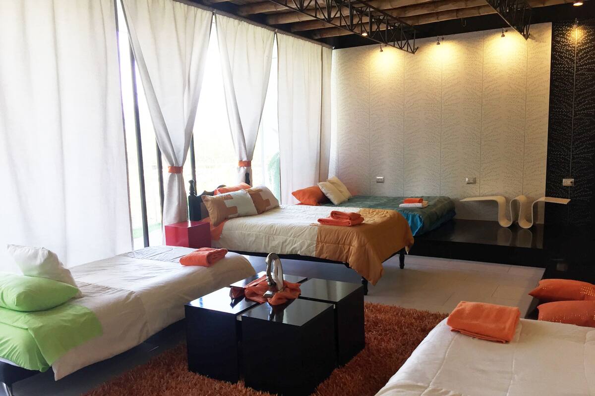 Ett hotellrum med två sängar, ett svart soffbord och en mjuk, orange matta.