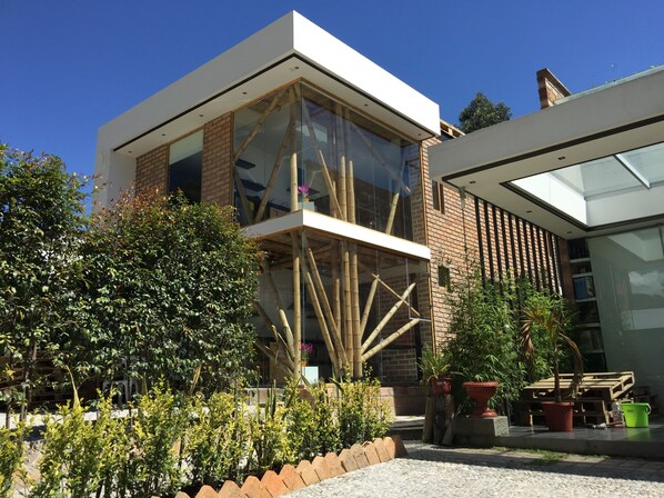A modern building with large glass windows, a brick facade, and a wooden structure in front.