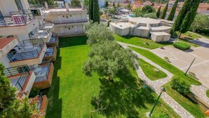 Un quartier résidentiel composé d’immeubles à plusieurs étages, doté d’une cour centrale verdoyante et entouré de végétation.