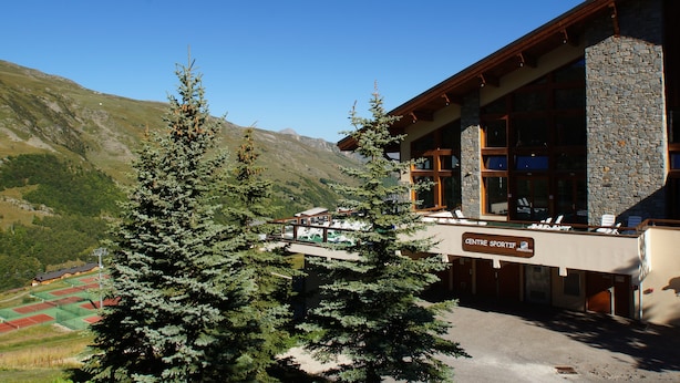 A mountain lodge with a stone facade, large windows, and a sign reading "Centre Sportif."