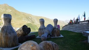 A sculpture garden with large wooden sculptures and flags in the background.