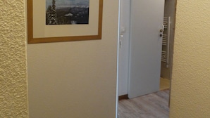 A hallway with a framed picture of a cable car on a mountain, a white door, and wooden flooring.