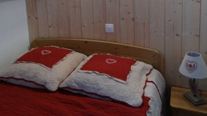 A wooden-paneled room with a bed, two red lamps, and a wooden cabinet.