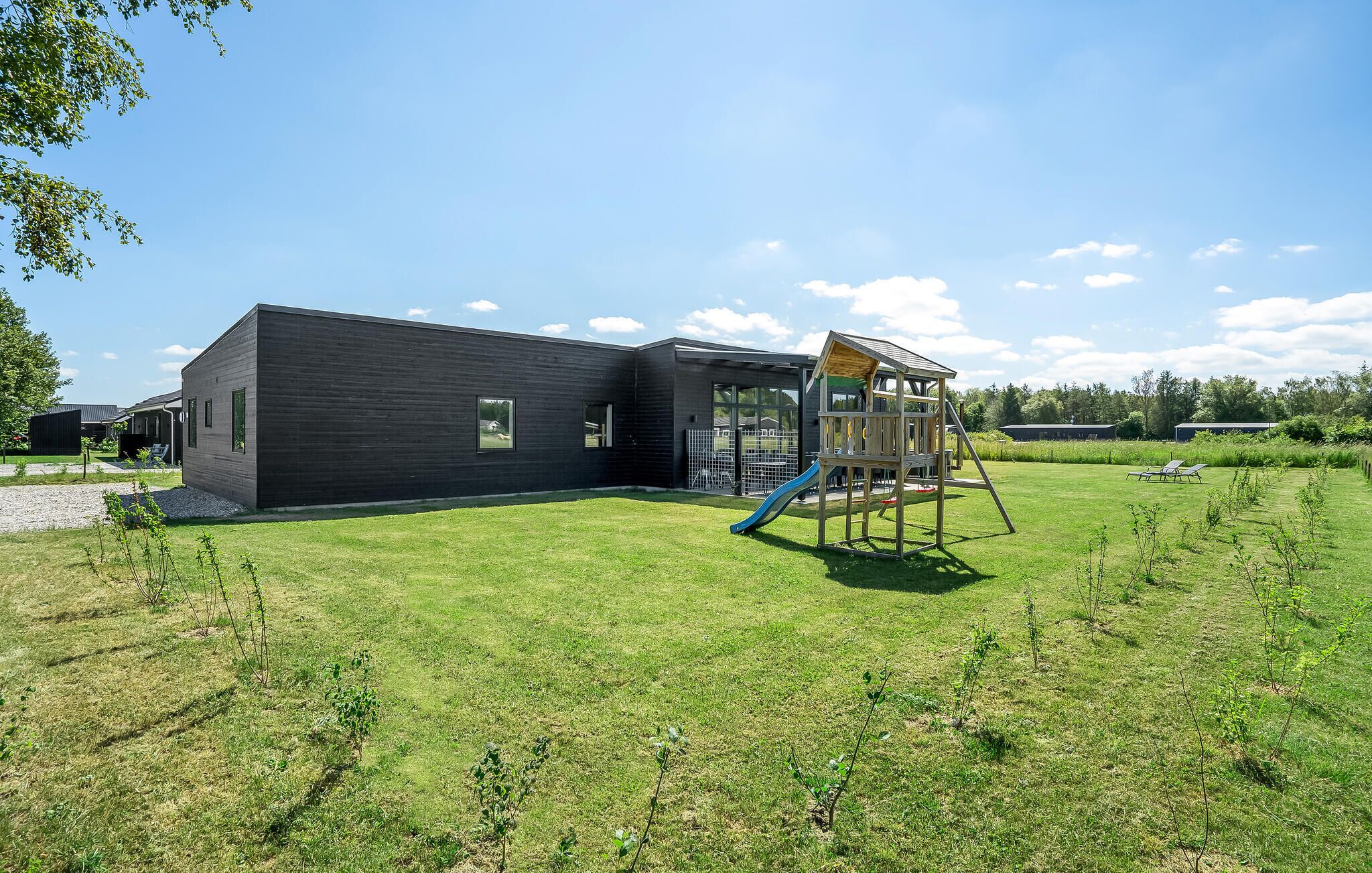 A modern building with a playground in a grassy area.