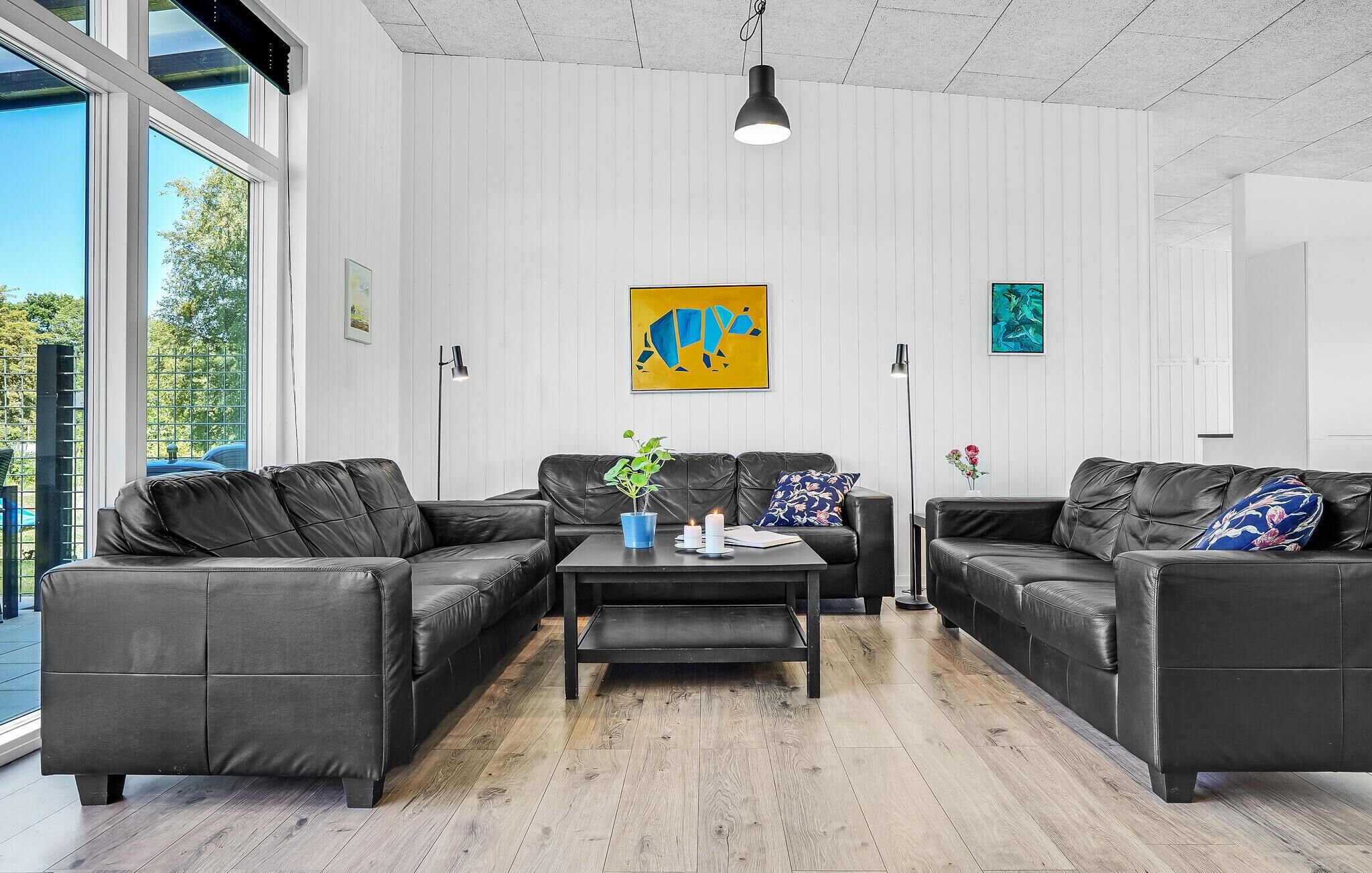Un salon moderne avec des canapés en cuir, une table basse et des œuvres d’art accrochées aux murs.