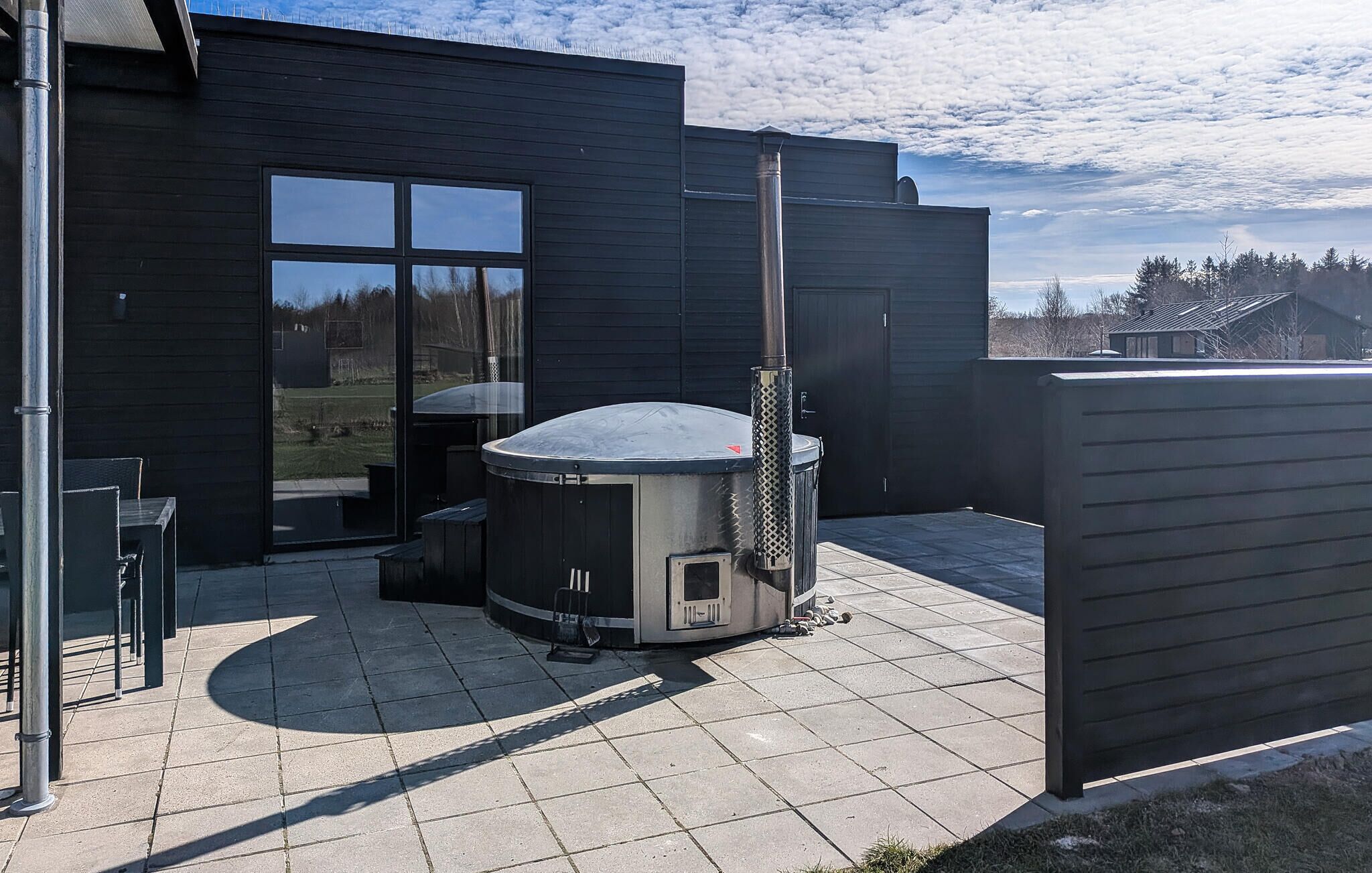 Une terrasse extérieure moderne dotée d’un jacuzzi, d’un barbecue et d’un espace salon abrité.