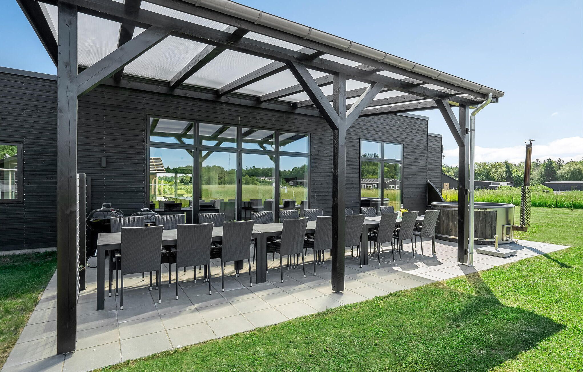An outdoor patio with a covered seating area, large windows, and a view of the surrounding landscape.