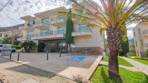 A multi-story building with balconies, a parking area, and a palm tree. - Rescator Resort 322 - One Bedroom Apartment, Sleeps 4 (Roses)