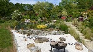 A garden with a gravel path, rocks, and a fire pit.