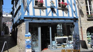 A traditional half-timbered building with a shop entrance, displaying various items and a signboard.