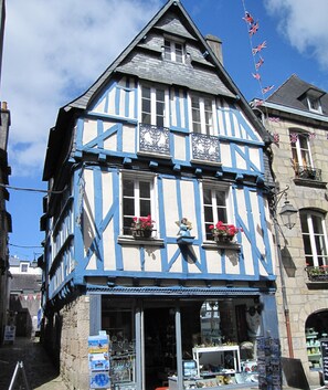 Un bâtiment traditionnel à colombages, avec une devanture de magasin où sont exposés divers articles et une enseigne.
