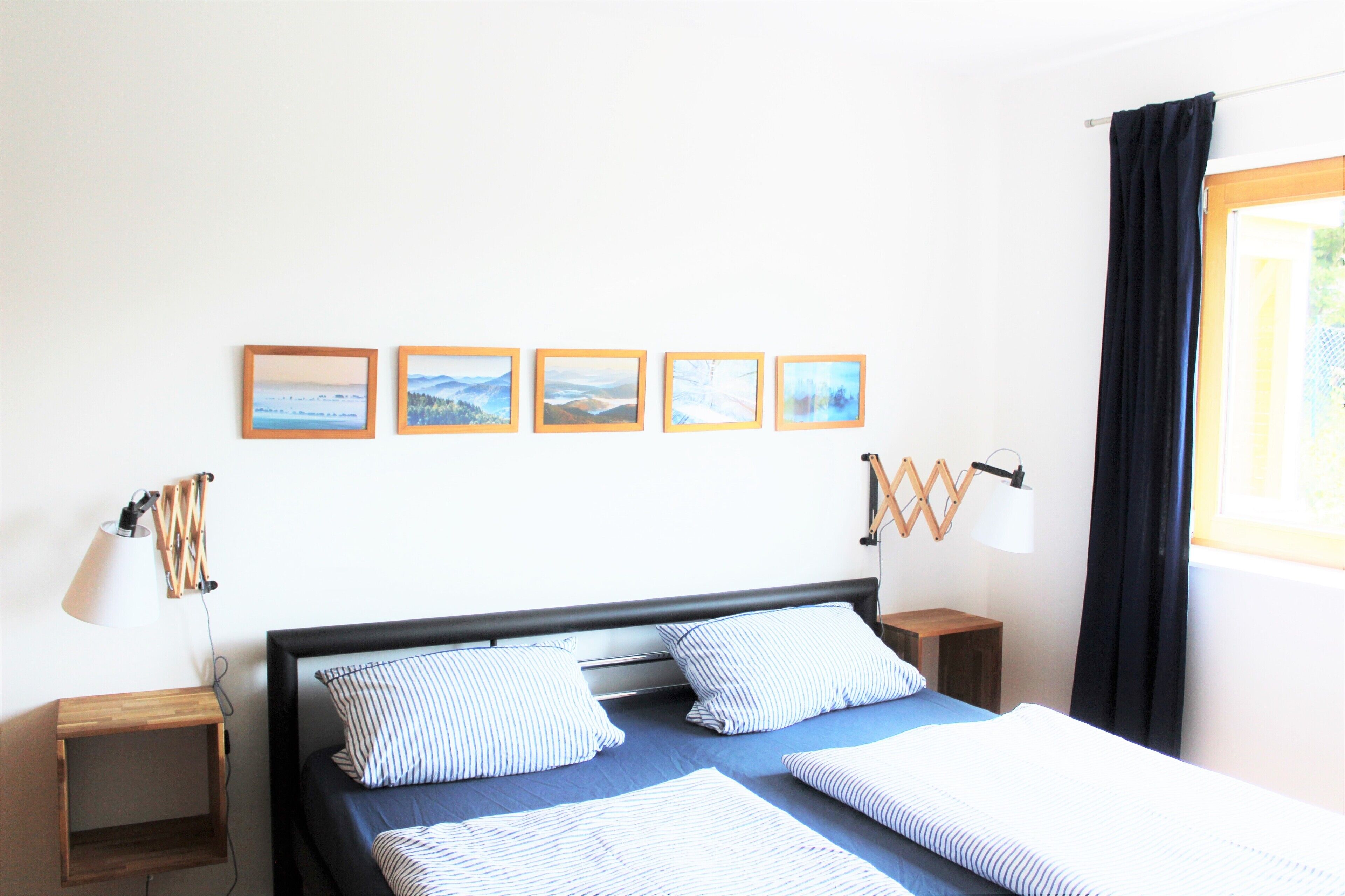 Een keurig opgemaakt slaapkamer met een bed, nachtkastjes en wanddecoratie.