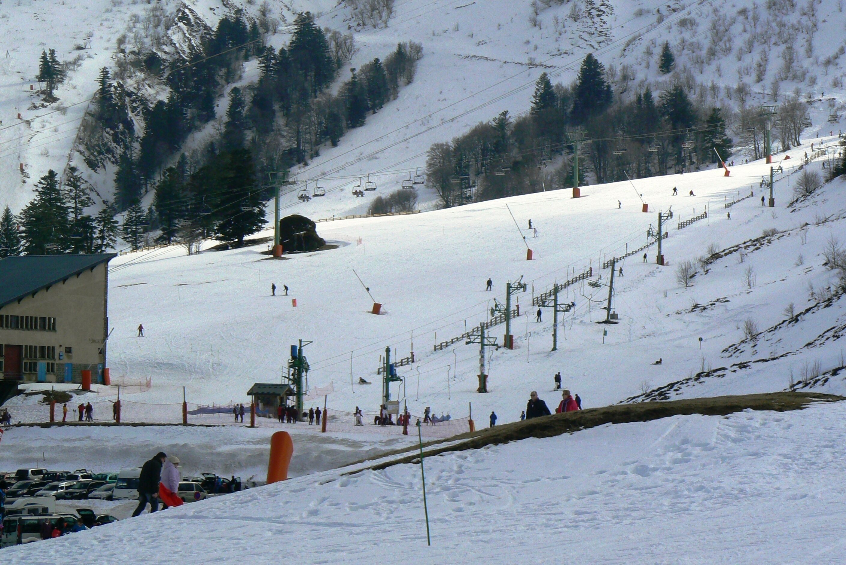 A ski resort with a chairlift, snow-covered slopes, and a building with a green roof.