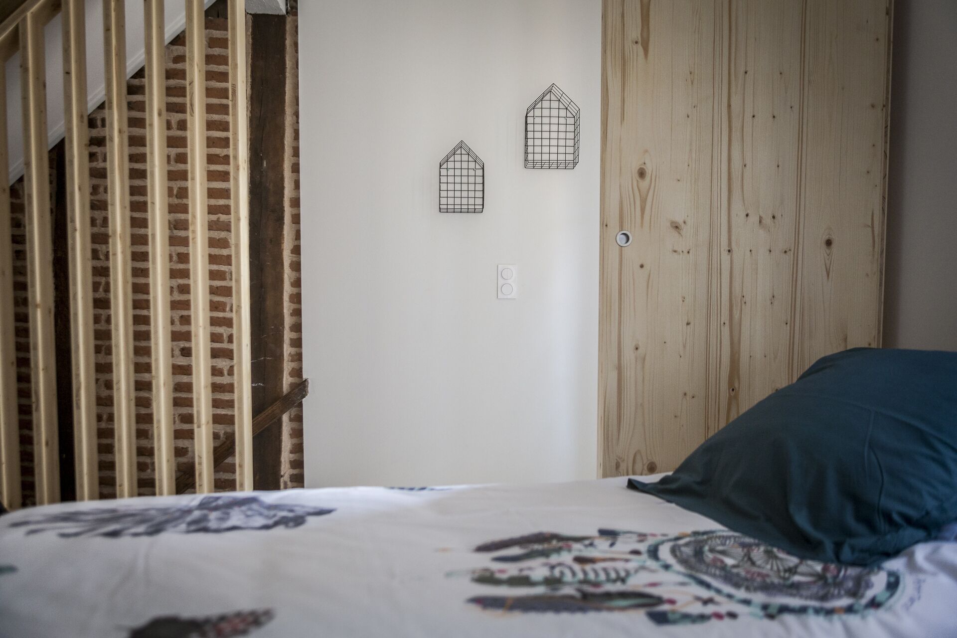 A bedroom with a bed, a wooden wardrobe, and two wall-mounted light fixtures.