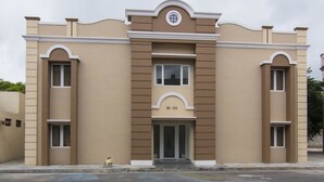 A two-story building with a symmetrical facade, a central entrance with a glass door, and a small circular window above the door.