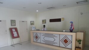 A reception area with a counter, framed pictures on the wall, a plant, and a signboard.