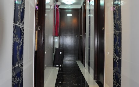 A hallway with a black marble floor, white walls, and a red curtain at the end.