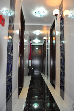 A hallway with a black marble floor, white walls, and a red curtain at the end. - Swiss Hostel (Kowloon)