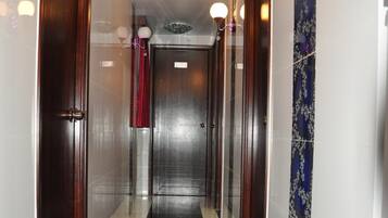 A hallway with dark marble flooring, wooden doors, and a patterned wall.
