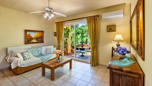 Ein gemütliches Wohnzimmer mit Sofa, Couchtisch und Blick auf den Garten durch eine Glastür.