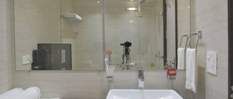 A modern bathroom with a large mirror, a sink, and a shower.