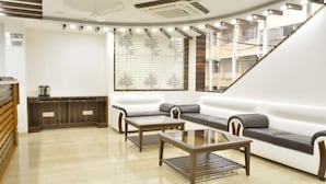 Eine moderne Lobby mit einer Couch, zwei Tischen, einem Empfangsbereich und einer Treppe.