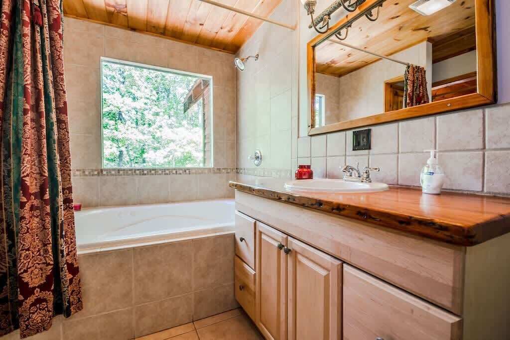 Ein Badezimmer mit Badewanne, Fenster, Waschbecken und Spiegel.