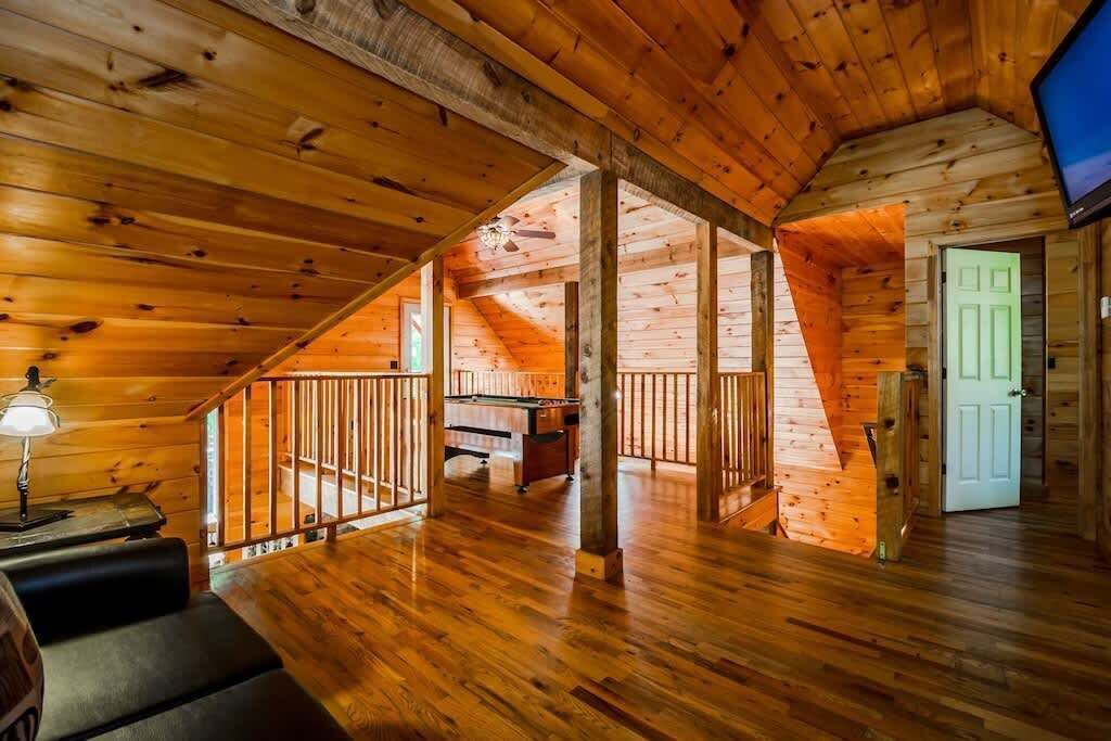 Un intérieur en bois avec une mezzanine, une table de billard et un téléviseur.