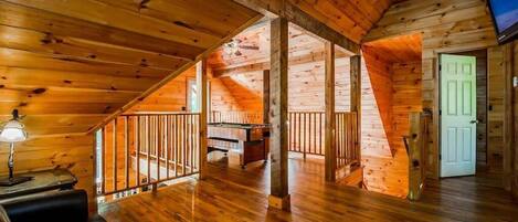 Un intérieur en bois avec une mezzanine, une table de billard et un téléviseur.