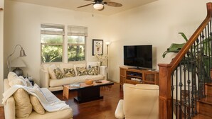 A living room with a sofa, armchair, coffee table, TV, and a staircase with a railing. - Private and Quiet, Luxury Family-Friendly unit in Fairways at Mauna Lani (Waimea)